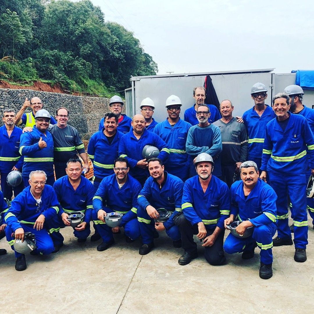 Equipe Futura reunida em obra, de macacão azul e capacete